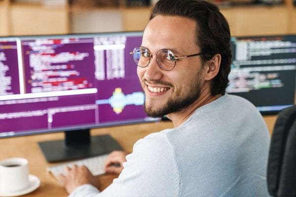 AI for HR Professionals: Man smiles at computer screen with code. AI in HR concept.