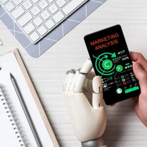 AI for Marketing: Robot hand holding phone with marketing analysis. Keyboard, notepad, and coffee on desk.