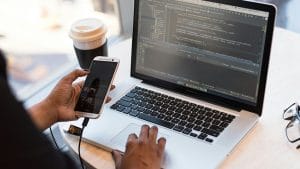 React and Redux web app development. Laptop with code, phone, and coffee.