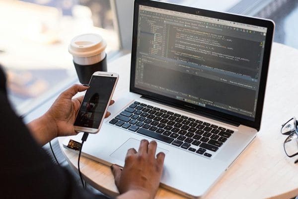 React and Redux web app development. Laptop with code, phone, and coffee.