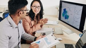 Data Science Foundations: Two analysts review charts and graphs on a computer and clipboard.