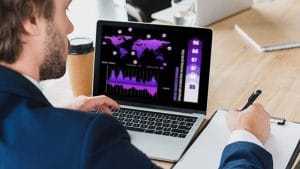 Data Structures and Algorithms in JavaScript: Man analyzing data on laptop with graphs and world map.
