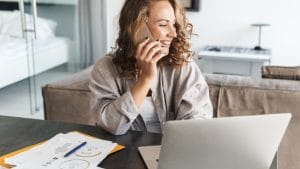 Executive Personal Assistant working at home. Woman on phone with laptop and paperwork.