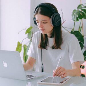 Office Admin: Woman with headphones using laptop and tablet. Online diploma in office administration.