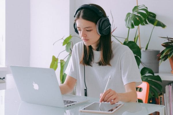 Office Admin: Woman with headphones using laptop and tablet. Online diploma in office administration.