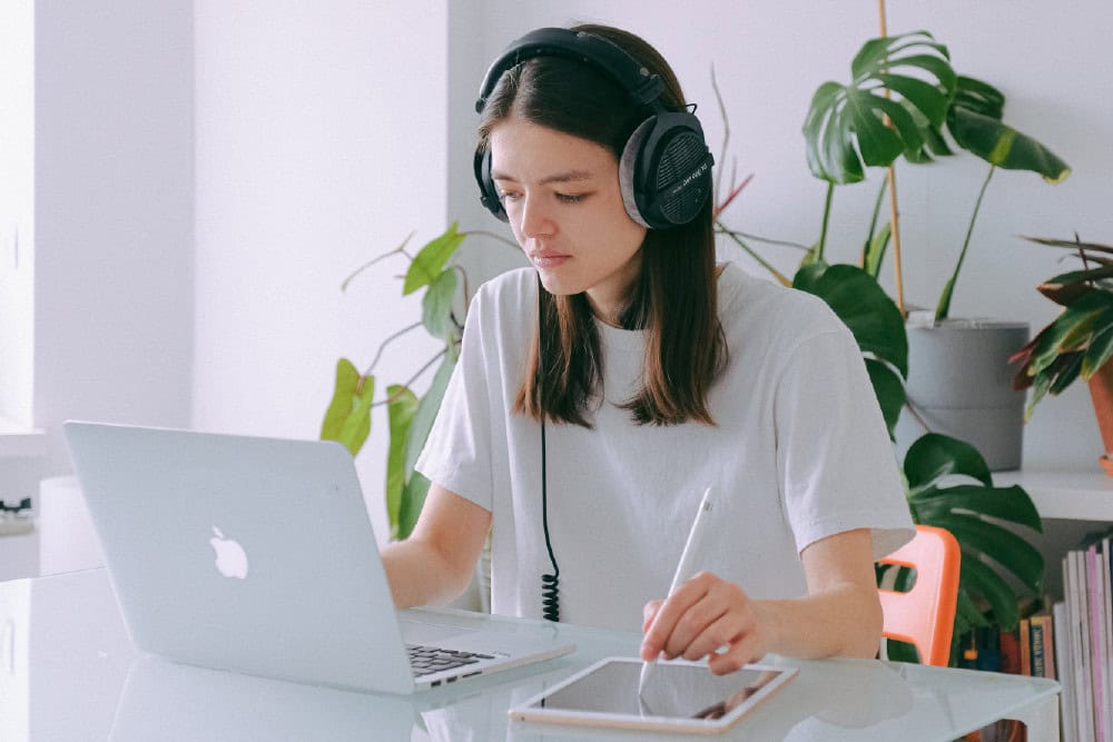 Office Admin: Woman with headphones using laptop and tablet. Online diploma in office administration.