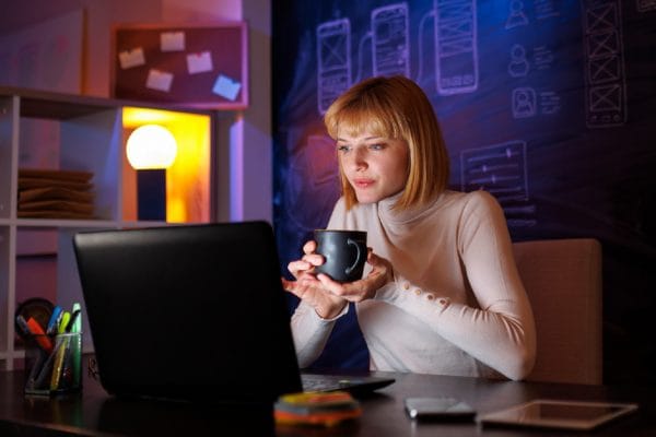 CloudOps Security Architect working on laptop, drinking coffee.