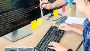 Security bundle: Programmer coding on desktop computer with security software.