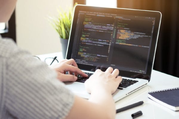 Software project lead working as advanced Scrum Master on laptop with code.