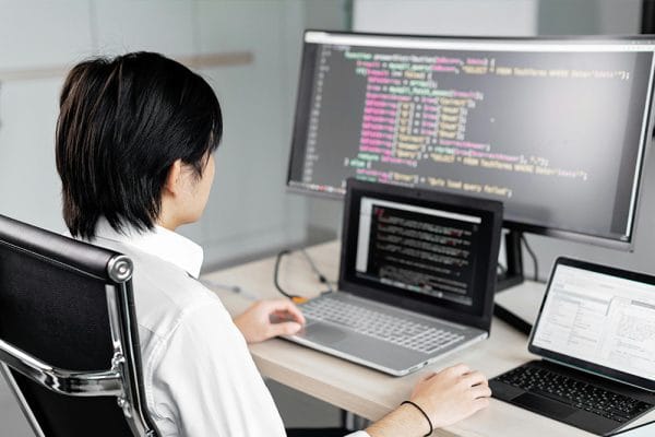 Developer working with code on multiple screens. Software engineering fundamentals.
