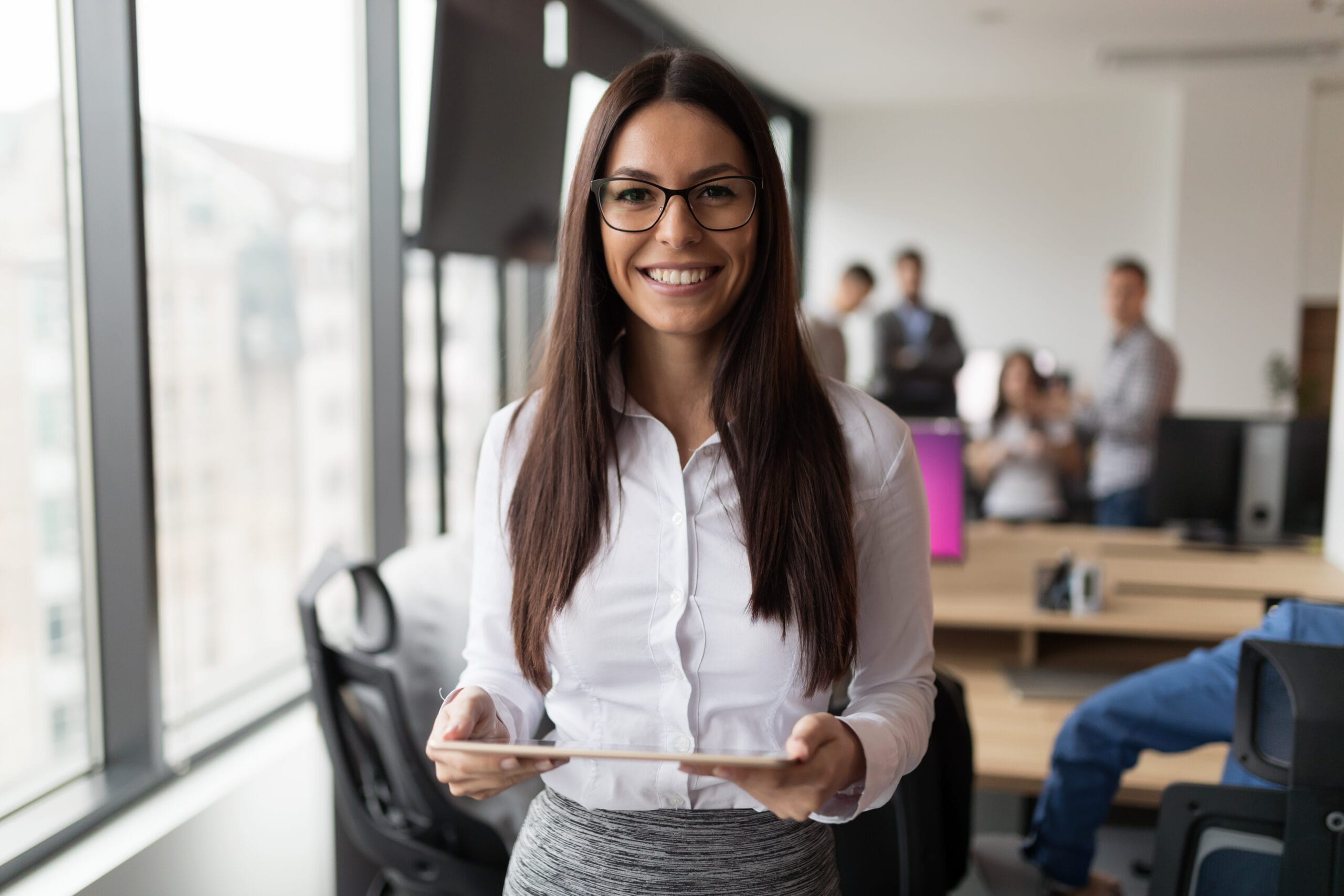 Smiling executive assistant holding tablet in office. Business woman career journey.