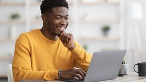 CCSP professional studying online. Happy African American man learning cloud security on laptop.