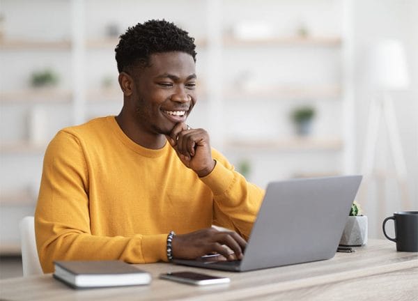 CCSP professional studying online. Happy African American man learning cloud security on laptop.