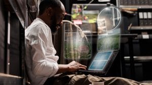 CloudOps Engineer works on laptop. Infrastructure support with digital interface.