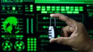 DevSecOps introduction: Hand holding a padlock in front of a green computer screen. Security concept.