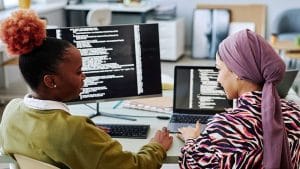 Two women programming. Learning programming principles, coding on computers.