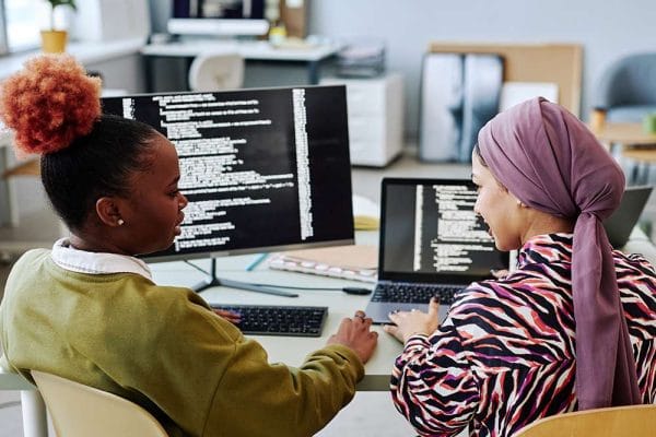Two women programming. Learning programming principles, coding on computers.