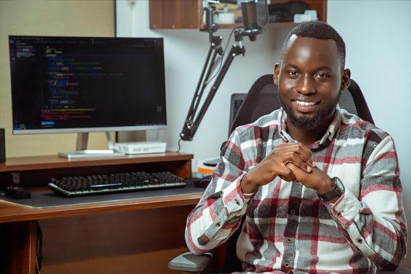 Java Novice to Javanista: Smiling programmer at desk with computer code. Software developer, coding, technology.