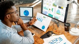 Data analyst using Power BI. Charts and graphs on computer and paper.