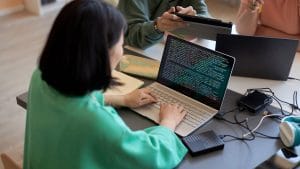 Woman coding Python Flask web app on laptop. Programming, development, learning.