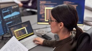 Security essentials: Woman analyzes data on multiple screens. Cybersecurity decision-makers use data to lead.