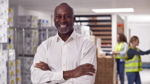 Smiling supply chain manager in warehouse. Logistics team, distribution, and inventory management.