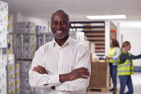 Smiling supply chain manager in warehouse. Logistics team, distribution, and inventory management.