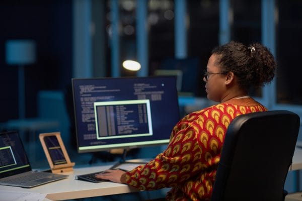 Woman using Linux on computer. Developer coding at desk with laptop. Using Linux.