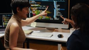 Web Apps with React and Redux: Two developers reviewing code on a computer screen.
