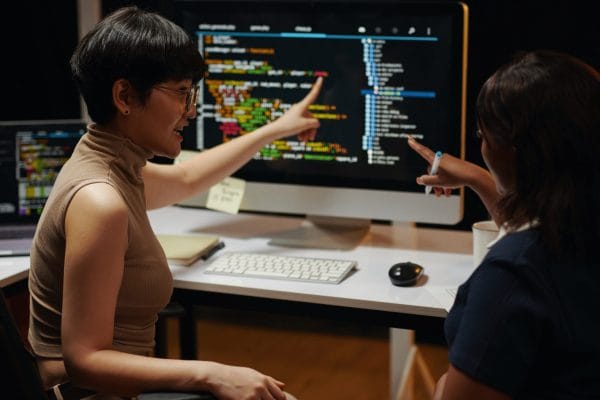 Web Apps with React and Redux: Two developers reviewing code on a computer screen.
