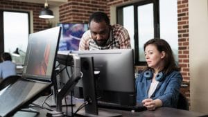 Windows desktop administration: Colleagues collaborate at computers in a modern office.