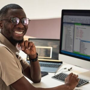 Man analyzing data with SQL. Developer smiling at computer screen with code. SQL programming.