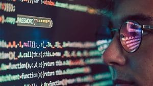 Cisco CyberOps Associate: Person with glasses looking at code. Cybersecurity professional, CBROPS certification.