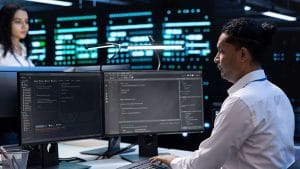 CompTIA CySA+ professionals analyzing cybersecurity data on dual monitors in a data center.