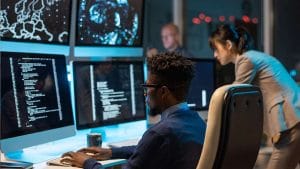 CompTIA PenTest+ team working. Cybersecurity professionals analyzing code on multiple monitors.