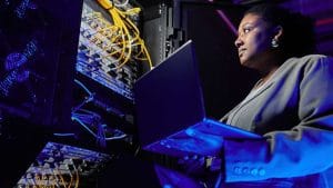 CompTIA Server+ candidate with laptop in data center. IT professional managing servers.