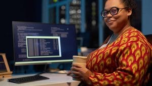 Woman studying for CompTIA A+, Network+, and AWS Certified Solutions Architect exams. Computer screen with code.