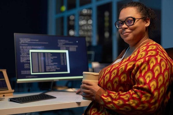 Woman studying for CompTIA A+, Network+, and AWS Certified Solutions Architect exams. Computer screen with code.