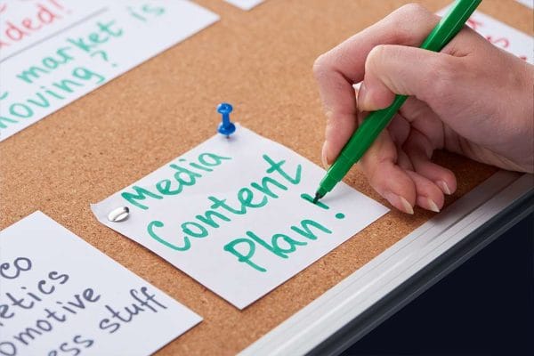 Content strategy planning on cork board. Hand writing Media Content Plan!.