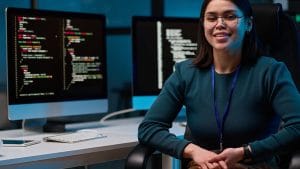 Creative coding with p5.js: Woman coding with two monitors displaying code. Programming with p5.js.