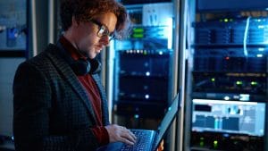 DevOps Engineer to Cloud Architect. IT professional working on a laptop in a server room. Cloud computing.