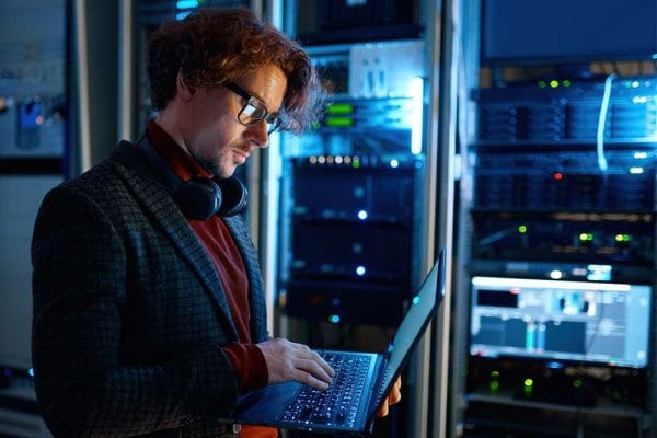 DevOps Engineer to Cloud Architect. IT professional working on a laptop in a server room. Cloud computing.