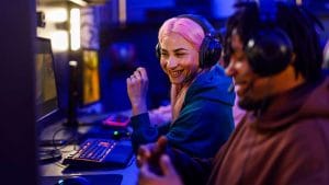 People developing a Phaser.js game. Coders with headsets, gaming keyboard, and computer screens.