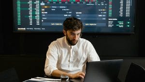 Google Data Engineer: Man analyzes financial data on laptop. Stock market charts displayed. Data analysis and engineering concept.