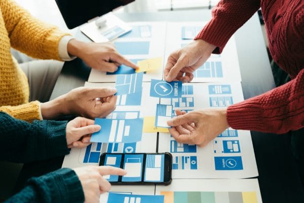 JQuery web design planning. Team using jQuery to create website layout on paper. Mobile app development with jQuery.