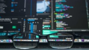 Glasses reflect code on a laptop screen. Developer to software architect concept.