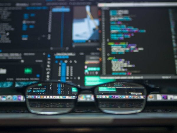 Glasses reflect code on a laptop screen. Developer to software architect concept.