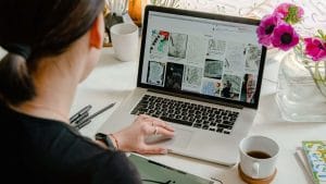 Woman studying mathematical literacy on laptop with coffee. Desk with flowers and tablet.