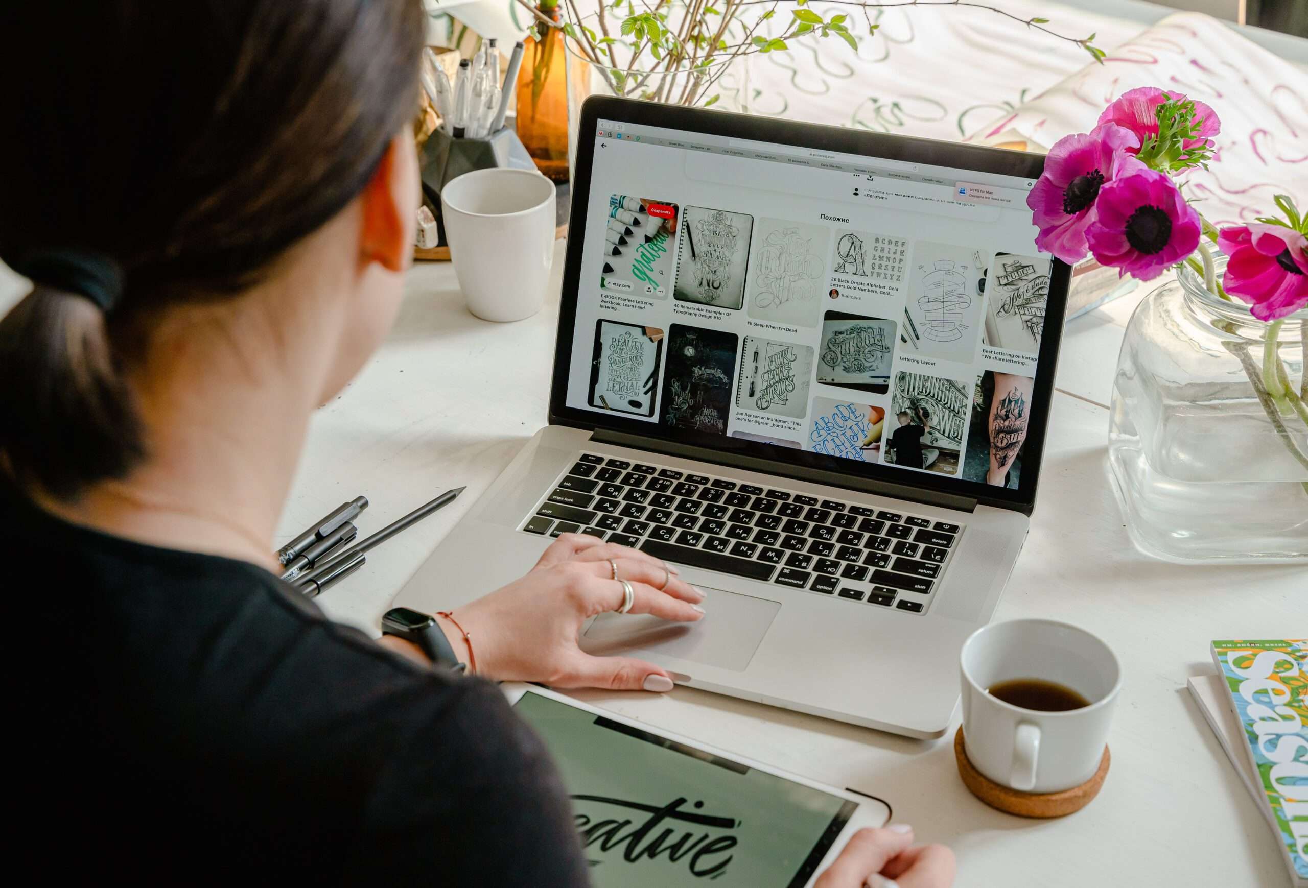Woman studying mathematical literacy on laptop with coffee. Desk with flowers and tablet.