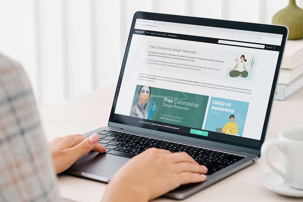 WordPress: Person using laptop. Screen displays Free Coronavirus Design Resources website.